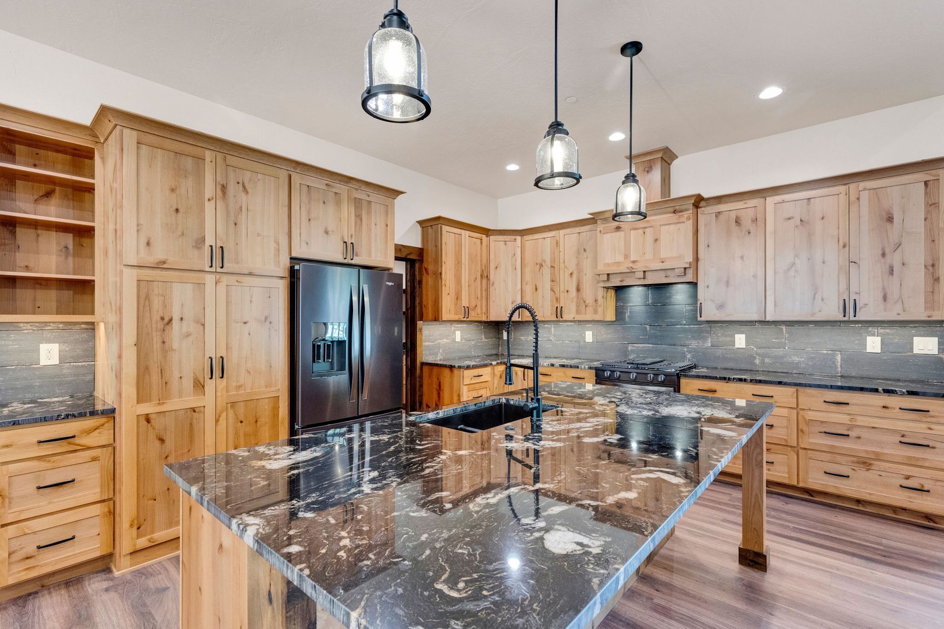 Modern kitchen with wood cabinets, black marble island, stainless appliances, and pendant lights