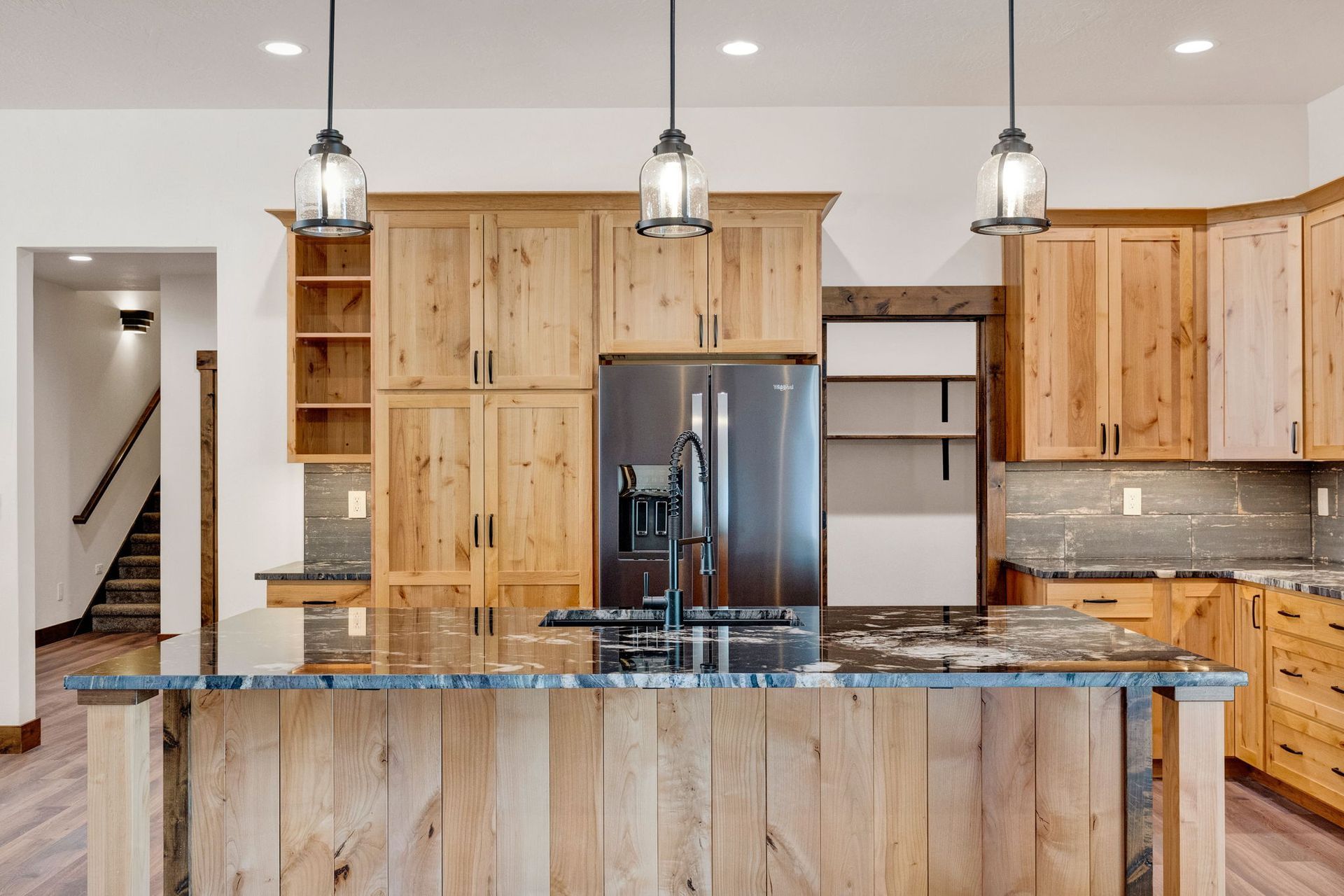 Modern kitchen with wood cabinets, stainless steel fridge, and granite island countertop