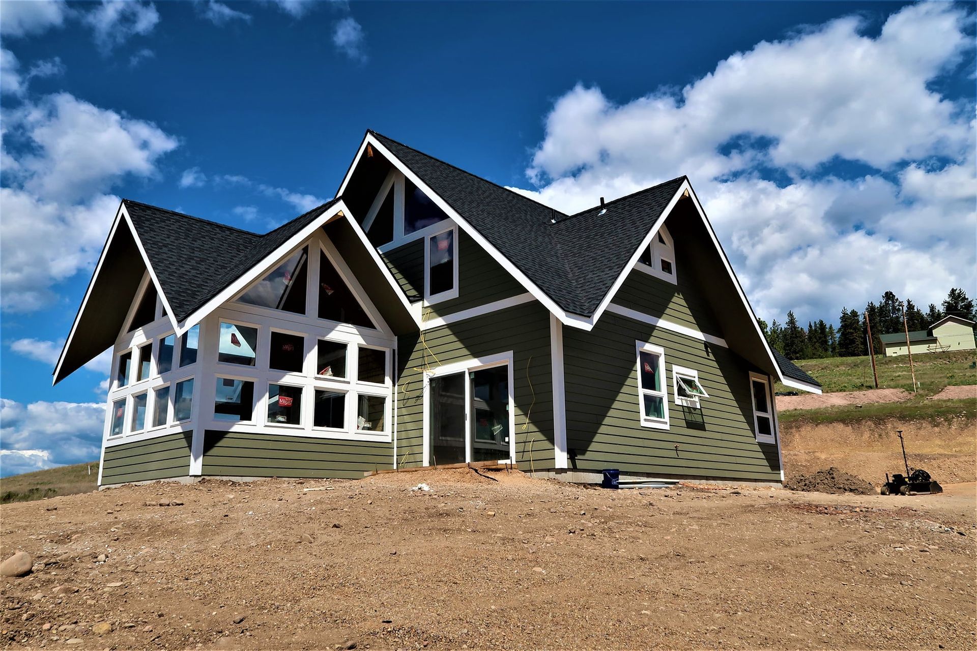 Modern house with black and white trim on a dirt lot under a bright blue sky