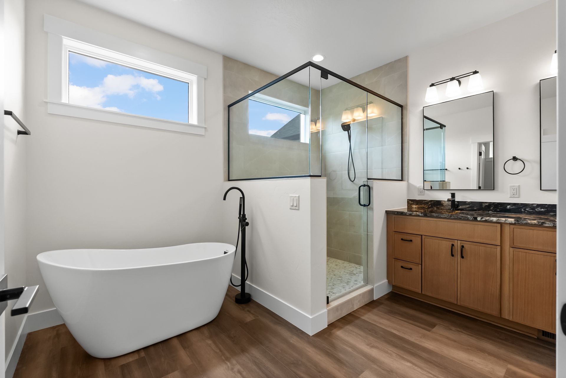 Modern bathroom with freestanding tub, glass shower, wood vanity, and large mirror
