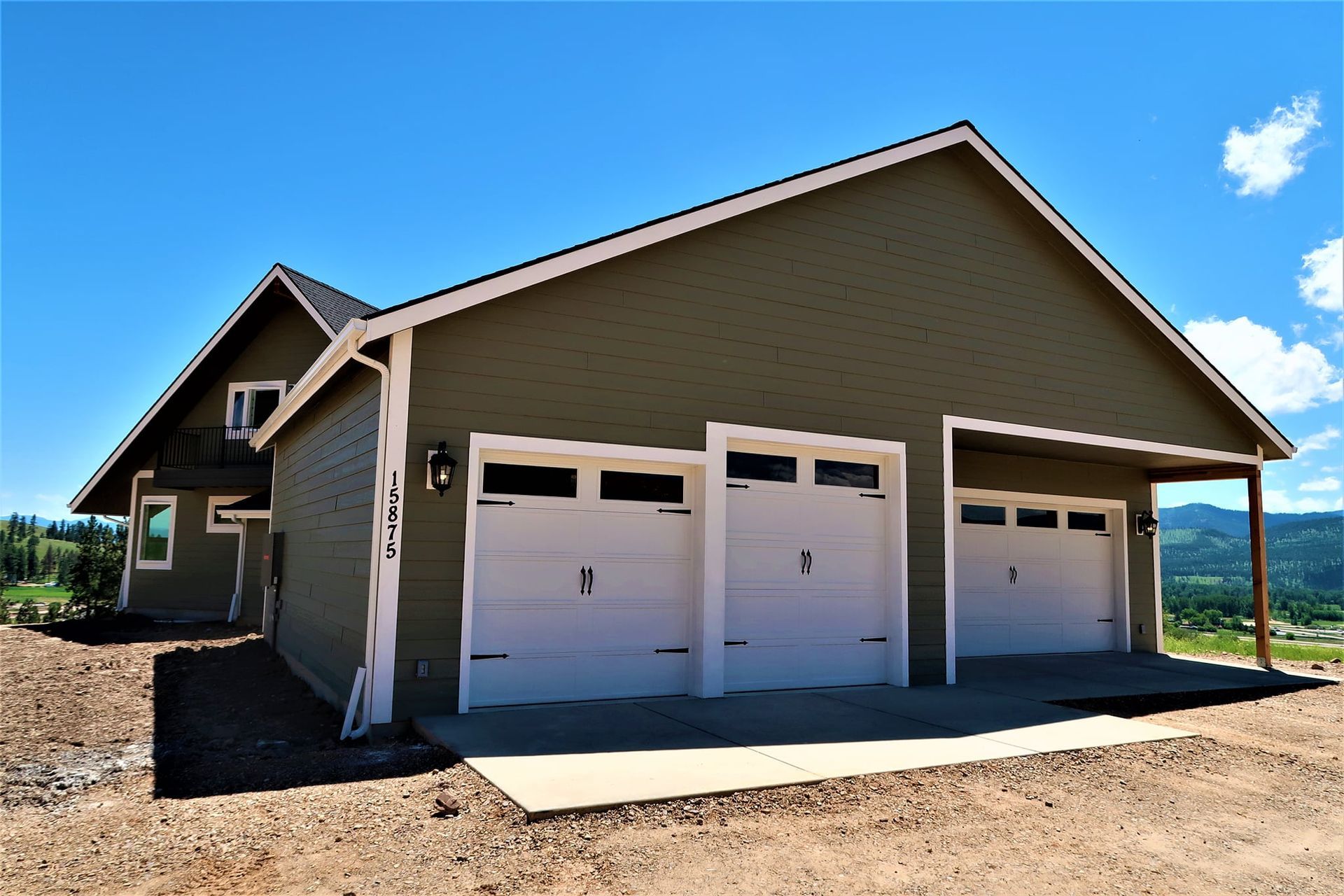 Three-car garage on a sunny day, with beige siding and gravel driveway