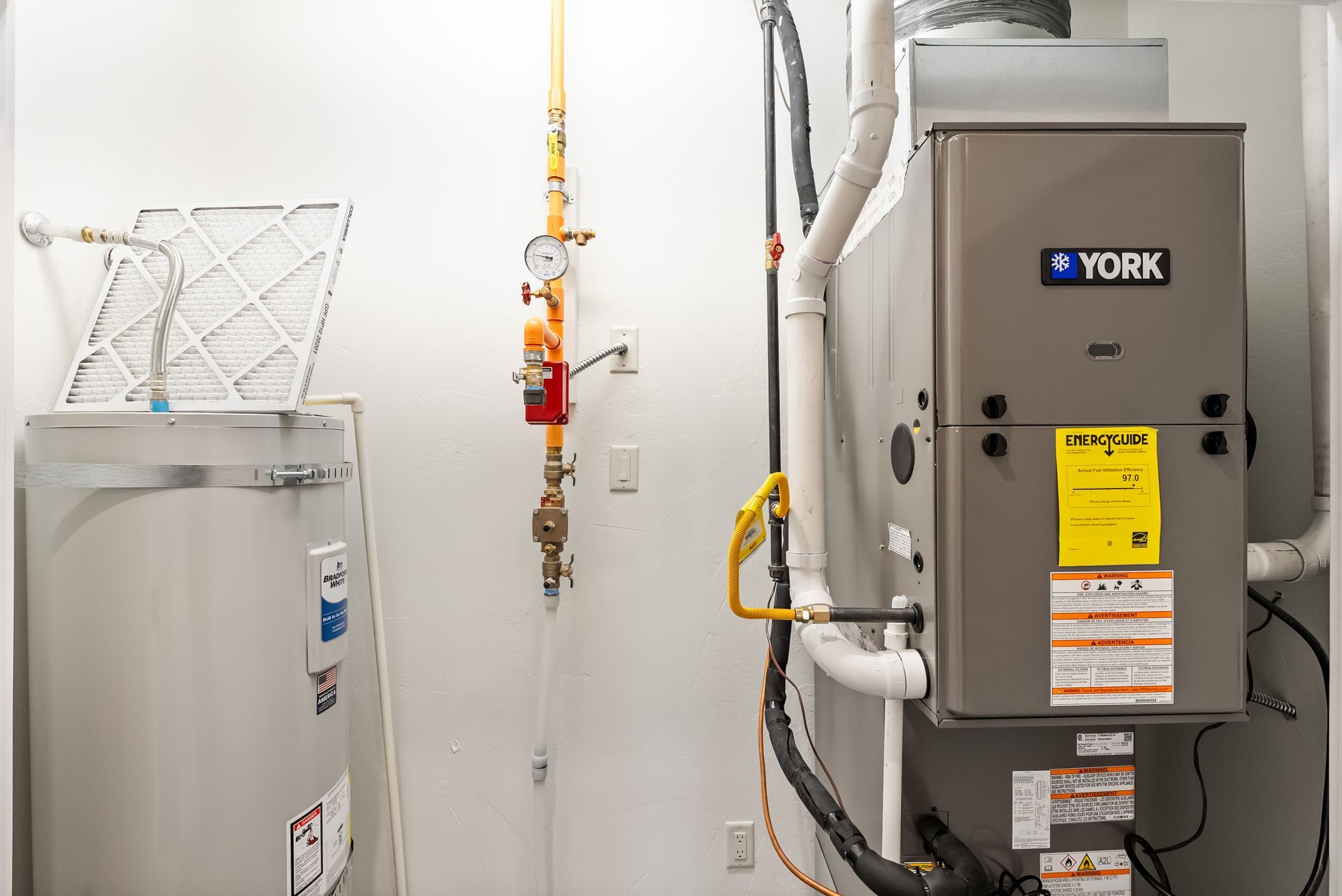 Laundry room with furnace, water heater, and utility piping against a white wall