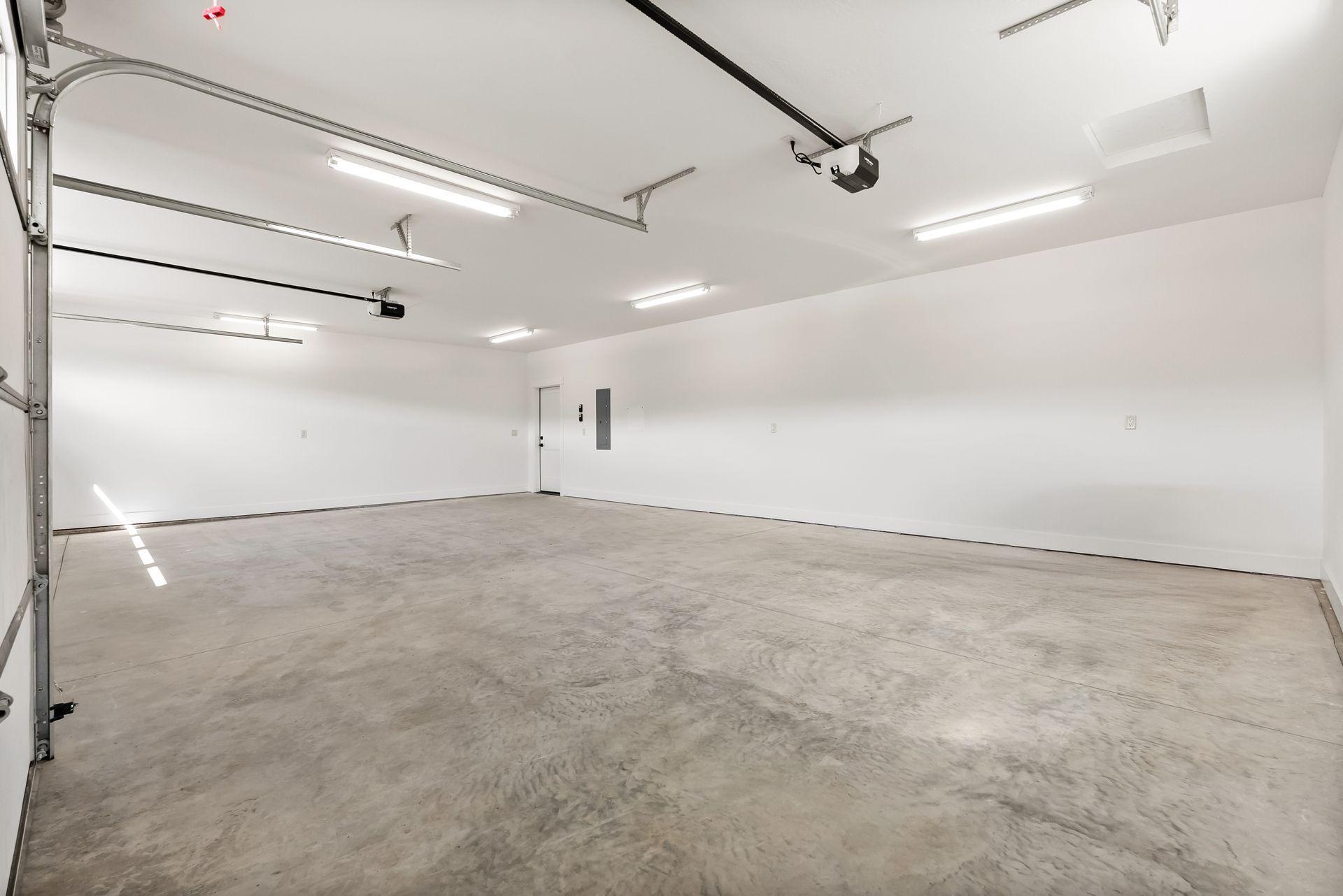 Empty white garage with concrete floor and overhead lights