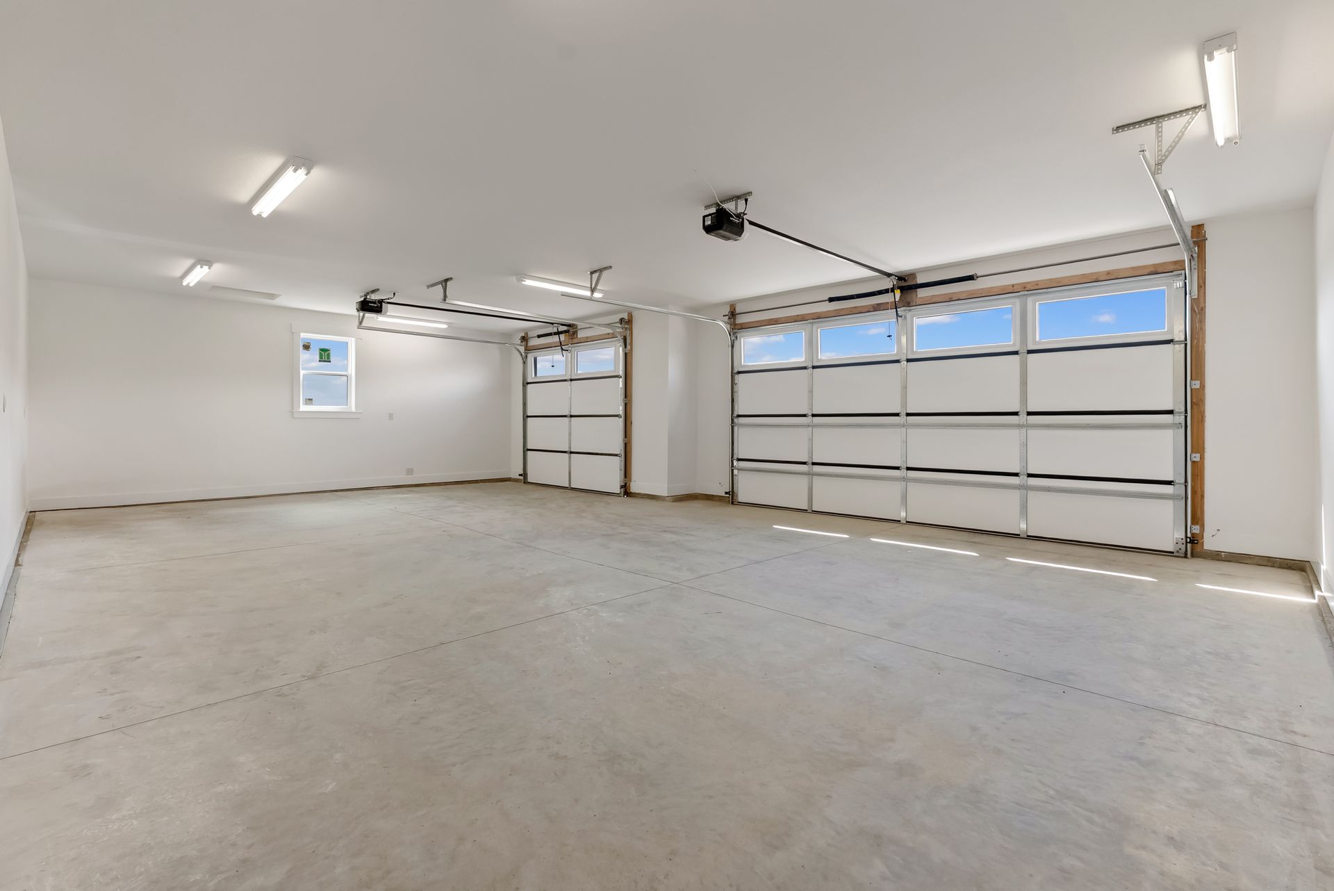Empty two-car garage with white walls, concrete floor, and closed double garage door.