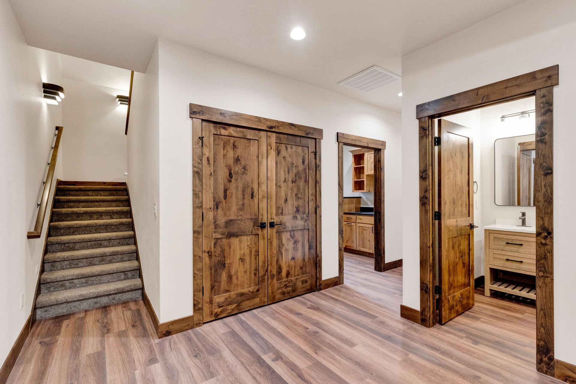 Modern rustic hallway with wood floors, barn doors, and stairs leading up on the left