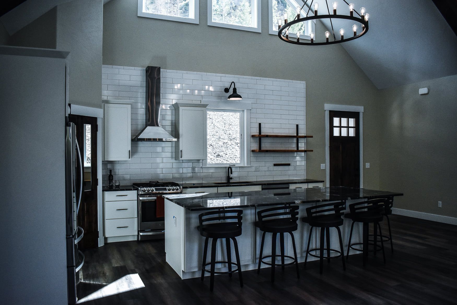 Modern kitchen with island, bar stools, white cabinets, and high windows in a spacious home interior