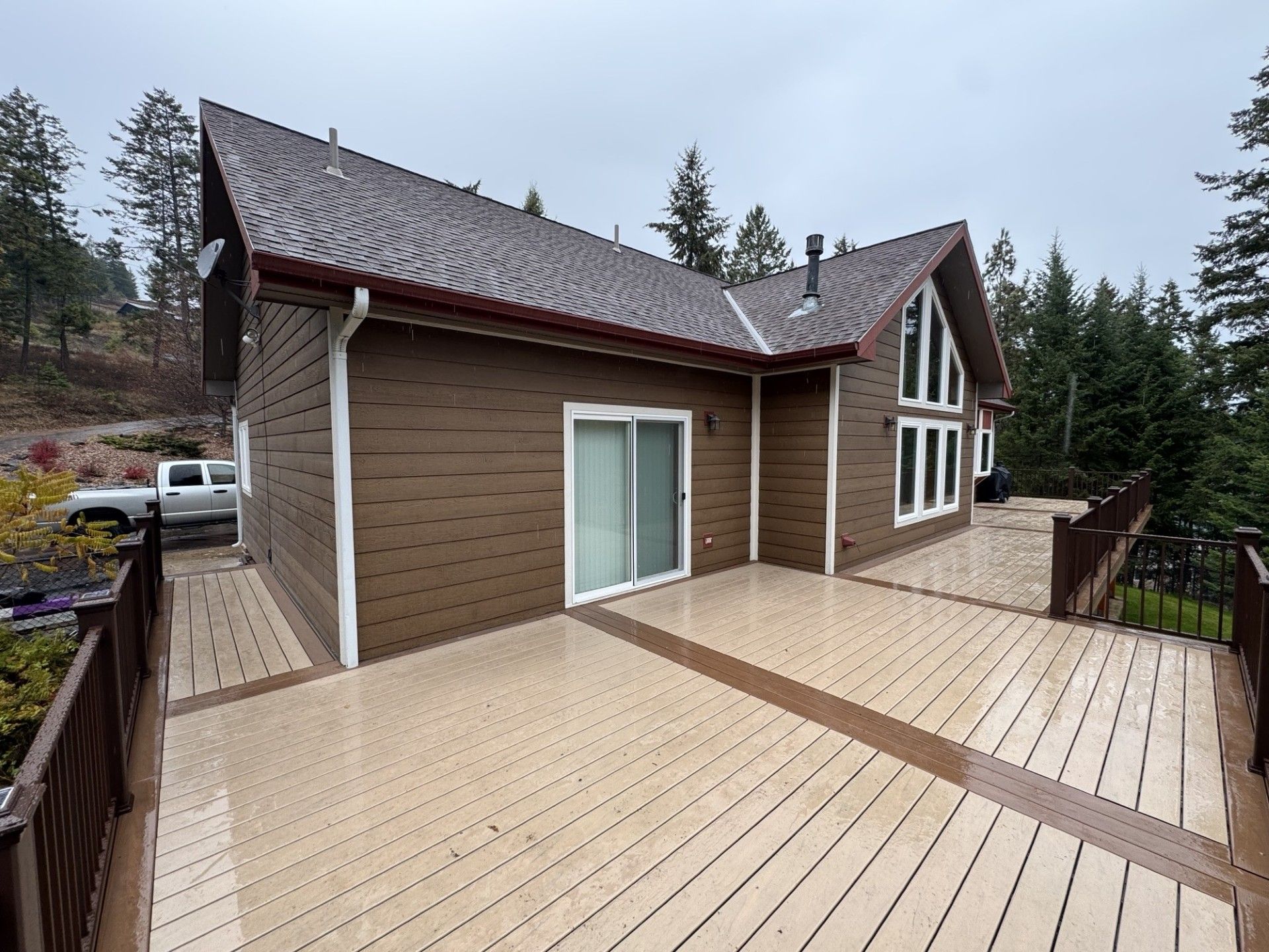Wooden house with a large deck and sliding glass doors under a cloudy sky