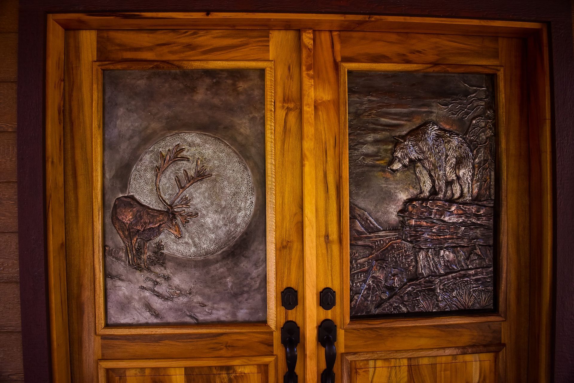 Wooden double doors with small painted panels showing a moon and a tree scene