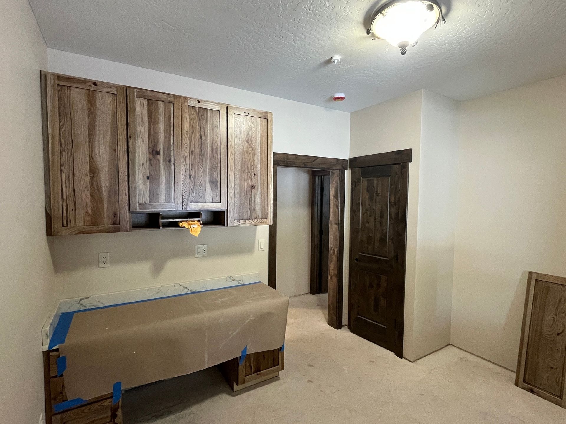 Small kitchen with wood cabinets, covered countertops, and a doorway on the right.