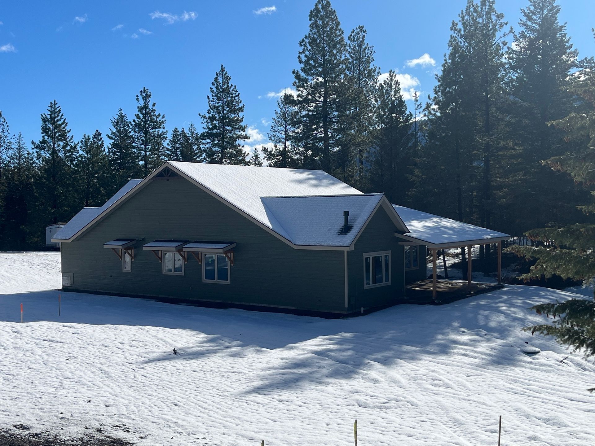 Snow-covered cabin in a pine forest on a sunny winter day