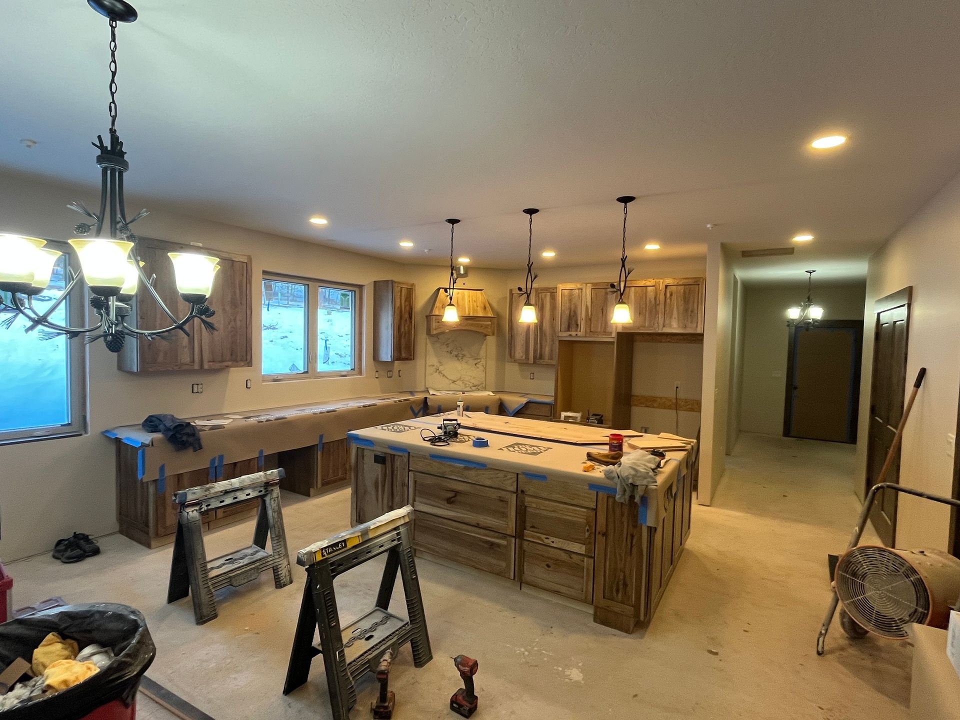 Kitchen under renovation with island, hanging lights, and tools on the floor