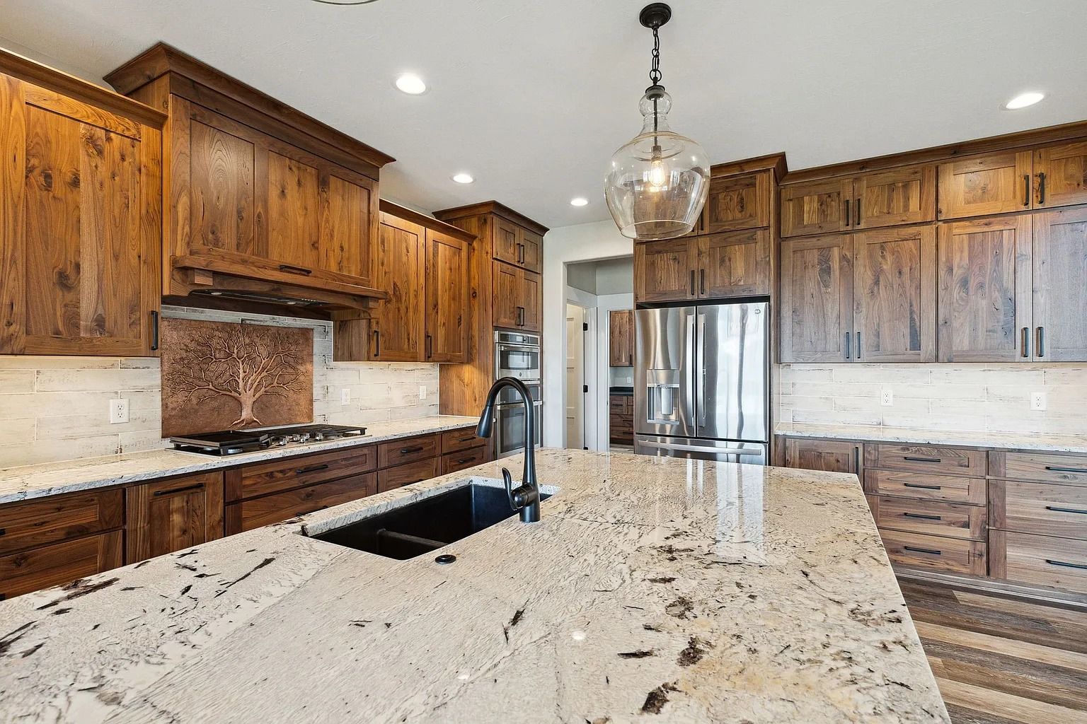 Modern kitchen with wood cabinets, granite island, stainless steel fridge, and pendant light