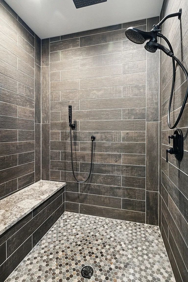 Modern tiled shower with pebble floor, wall-mounted showerheads, and a built-in bench