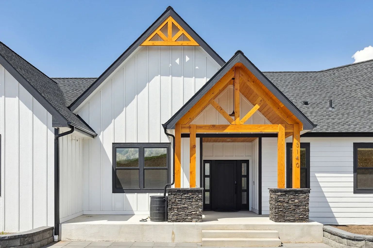 Modern white house exterior with black trim and wood-accented front porch and gable