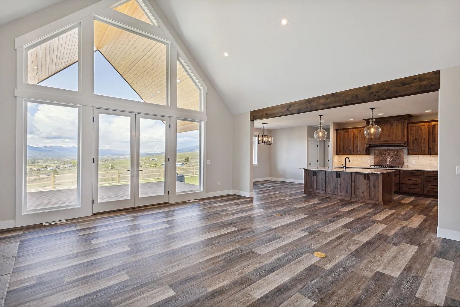 Bright open-concept living room with vaulted ceiling, large windows, and a modern kitchen island