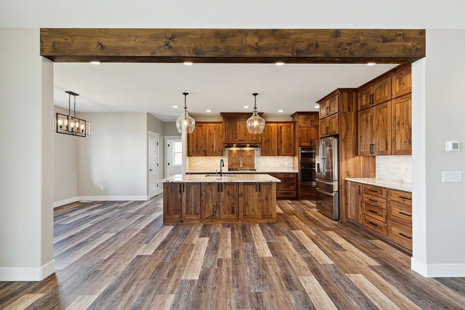 Open-concept kitchen with wood cabinetry, island, stainless appliances, and patterned wood-look flooring