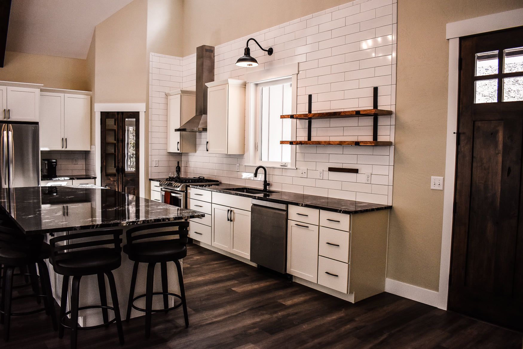 Modern kitchen with white cabinets, black island stools, and dark wood floors