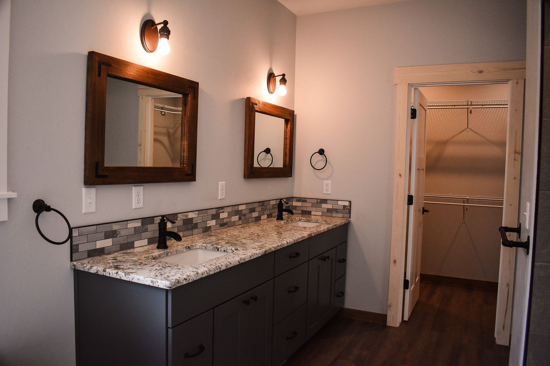 Bathroom vanity with granite countertop, double mirrors, and open doorway to a shower room