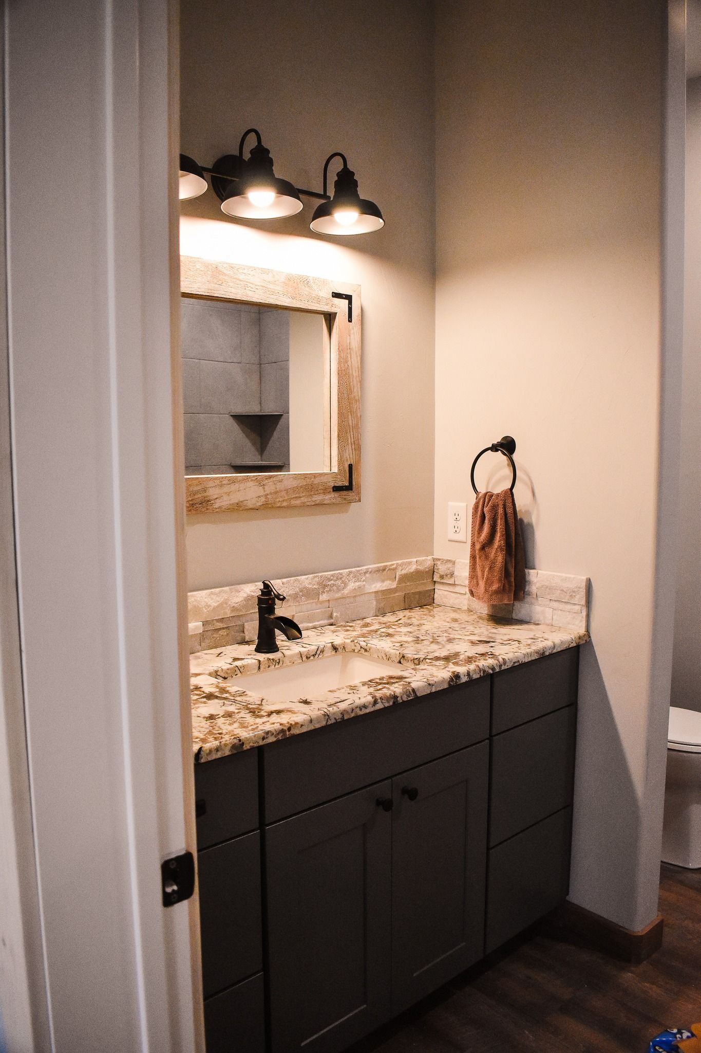 Bathroom vanity with granite countertop, mirror, and wall-mounted light fixture.