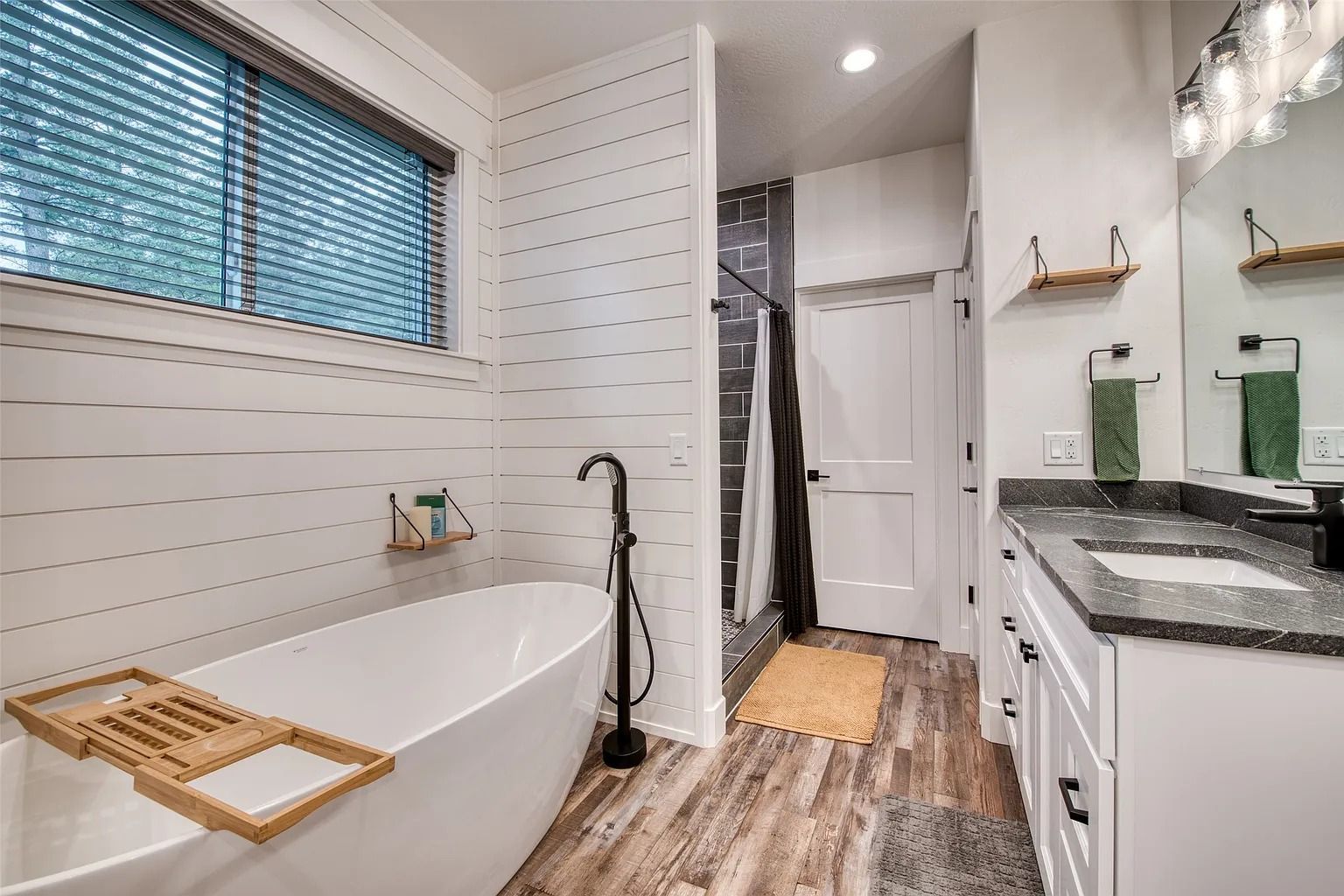 Bright white bathroom with freestanding tub, shower, vanity, and wood-look floor