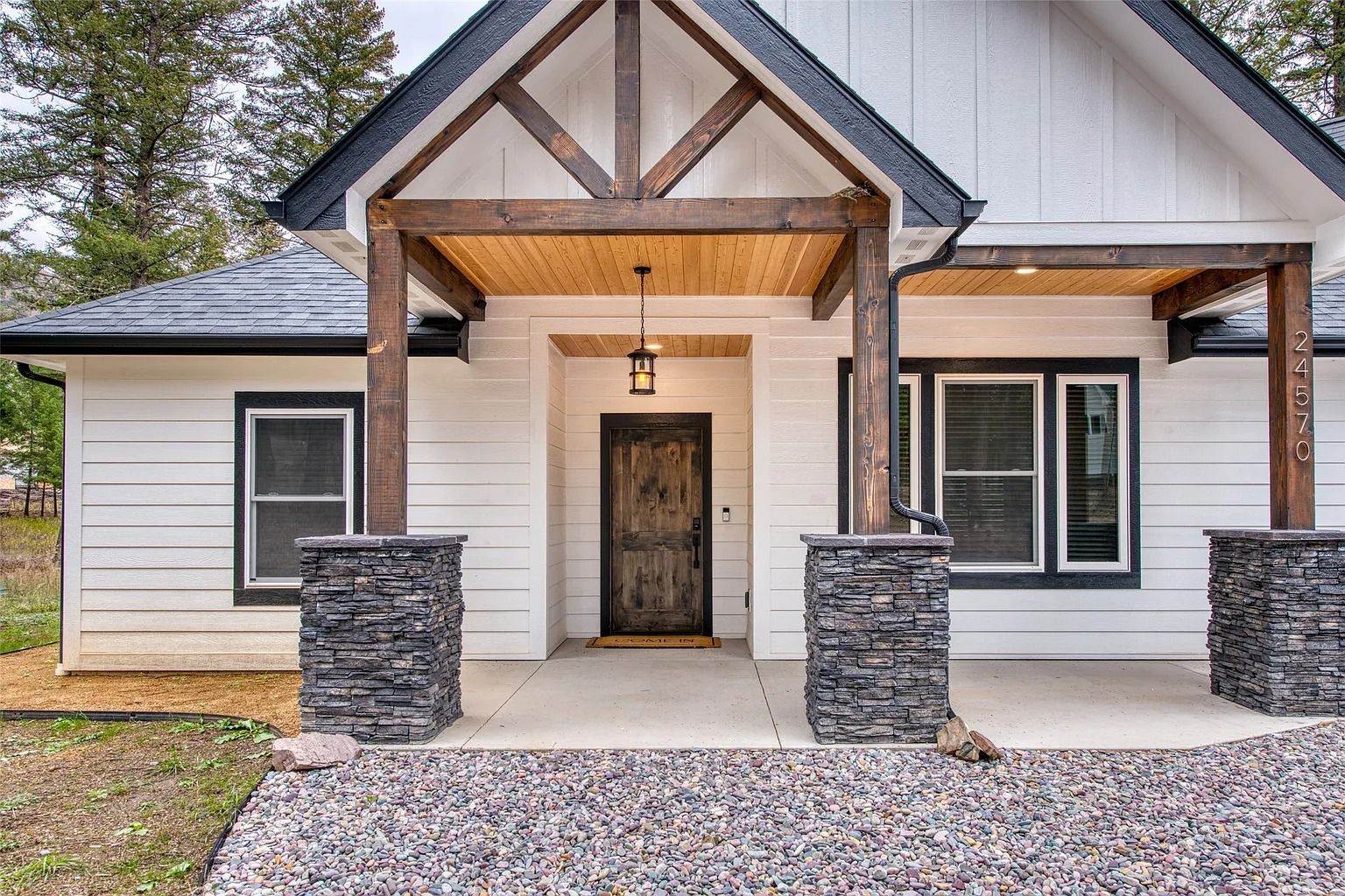 Front view of a modern white house with stone porch columns and a covered entryway