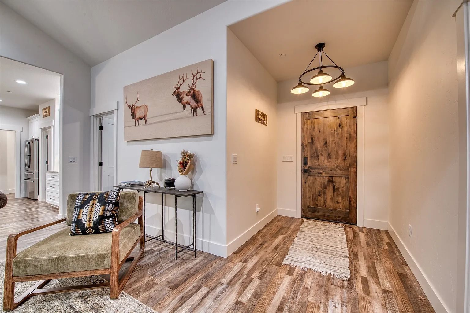 Small entryway with wood floors, bench, console table, and rustic front door in a bright hallway