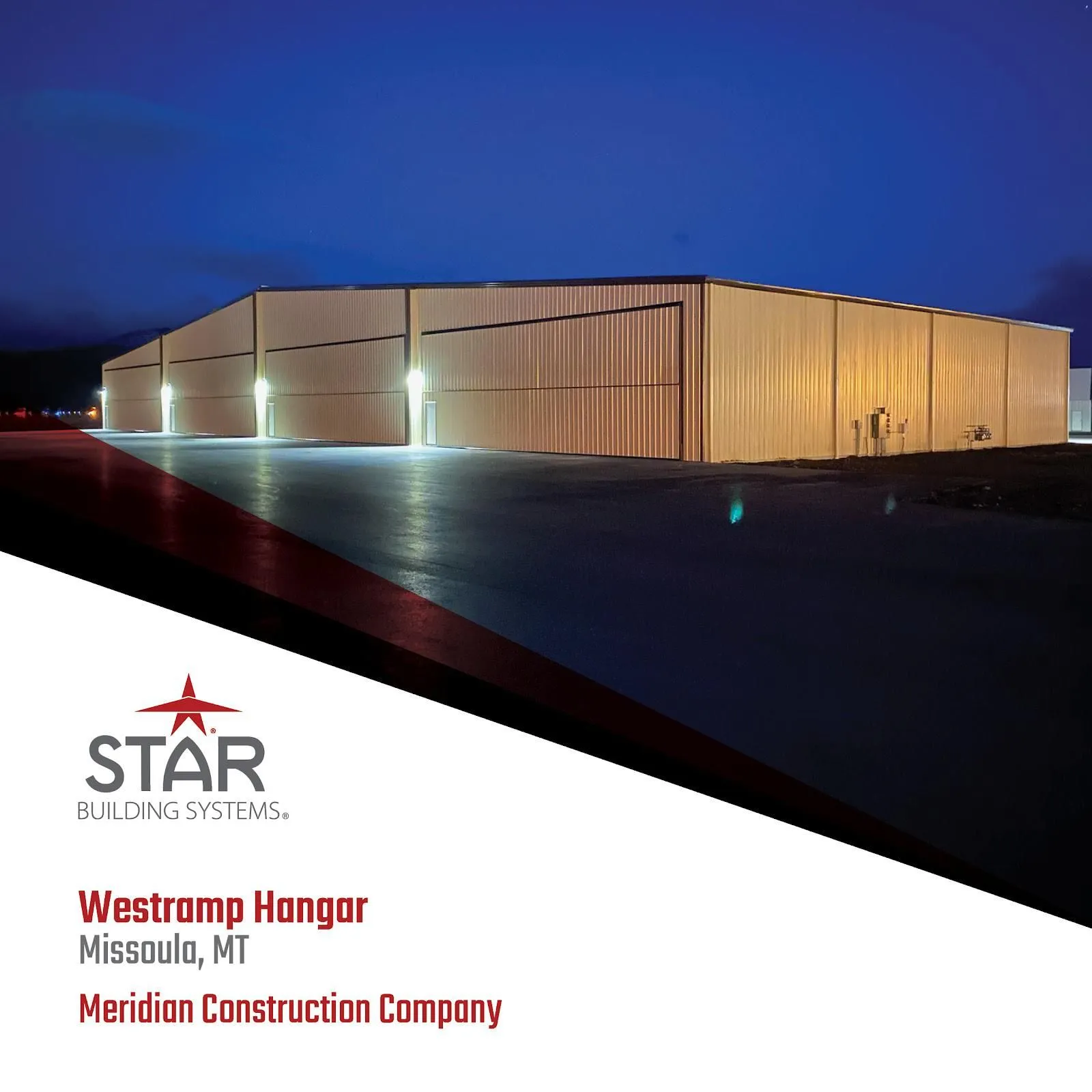 Westrom Hangar at sunset, illuminated white building in Missoula, MT, with STAR logo and Meridian Construction Company.