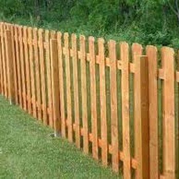 A wooden picket fence is sitting on top of a lush green field.