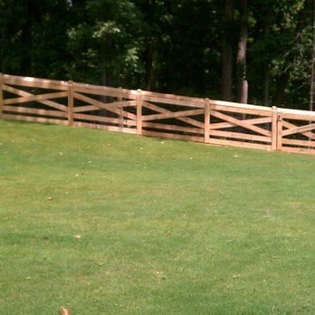 A wooden fence surrounds a lush green field