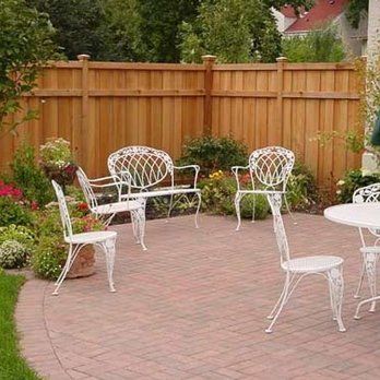 A wooden fence surrounds a patio with a table and chairs.
