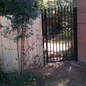 A wooden fence with a metal gate in front of it