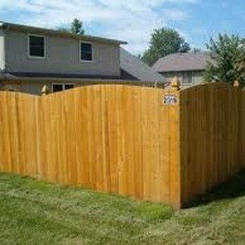 A wooden fence is in the backyard of a house.
