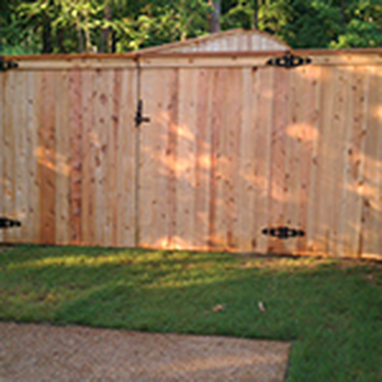 A wooden fence is sitting on top of a lush green lawn next to a driveway.