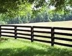 A black and white wooden fence surrounds a grassy field.