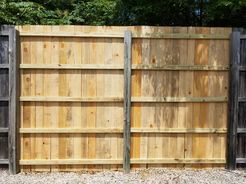 A wooden fence is sitting on top of a gravel driveway.