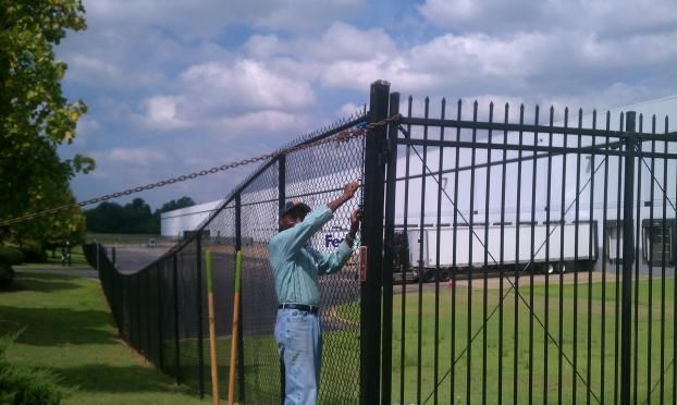 A man is working on a chain link fence.