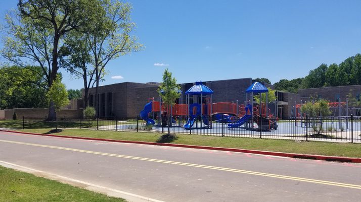 A playground is sitting on the side of the road in front of a building.