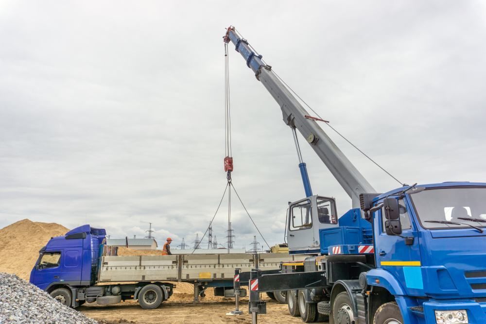 A Crane Is Lifting A Concrete Slab From A Truck At A Construction Site — Port Stephens Cranes In Cessnock, NSW