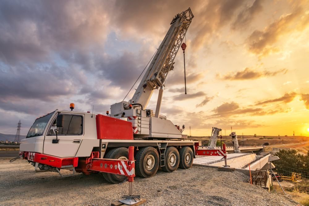 A Large Crane Is Sitting On Top Of A Gravel Road At Sunset — Port Stephens Cranes In Raymond Terrace, NSW
