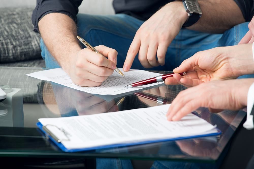 A Group Of People Are Sitting At A Table Signing A Document — Port Stephens Cranes In Salt Ash, NSW