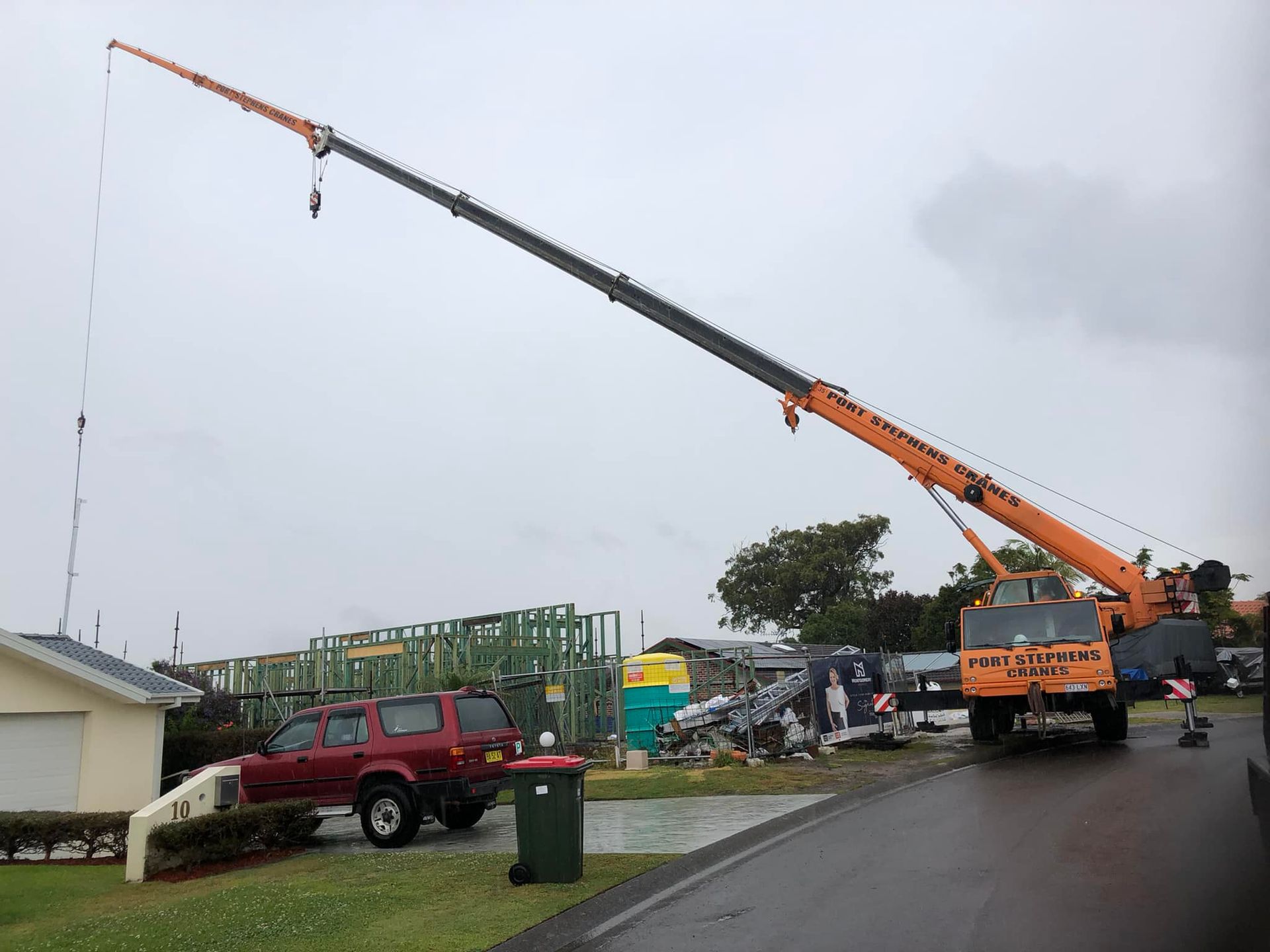 A Man Is Working On A Scissor Lift At A Construction Site — Port Stephens Cranes In Lake Macquarie, NSW