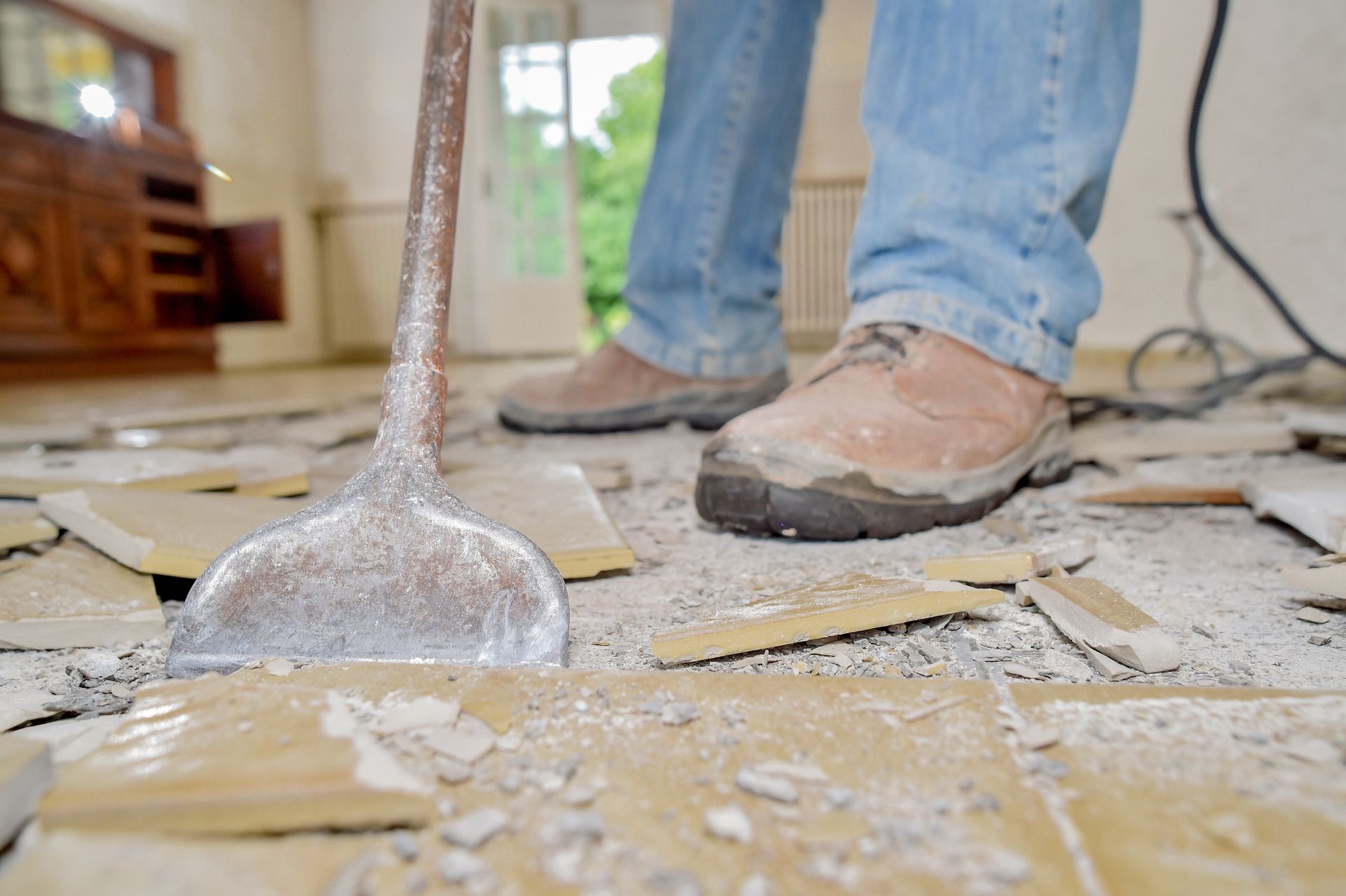 A man shovels debris from the floor, focused on cleaning the area efficiently.