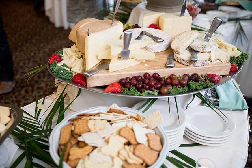 Cheese and crackers platter with various cheeses, grapes, strawberries, and crackers.