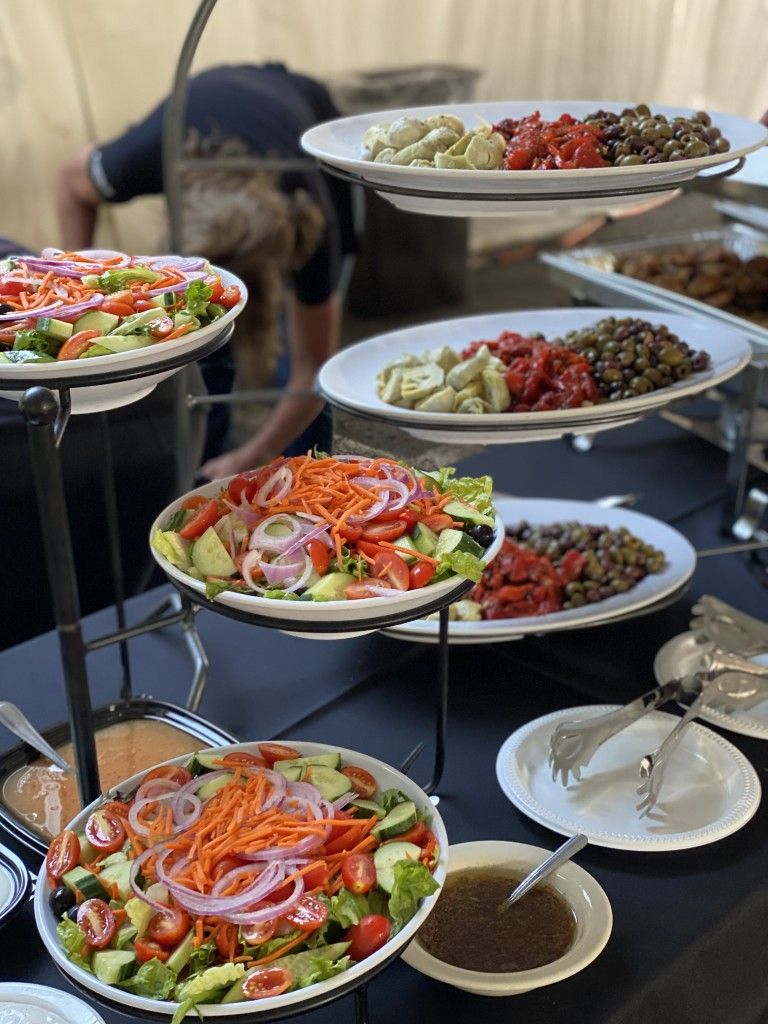 Salad bar with tiered serving stand, various salad ingredients, and dressing.