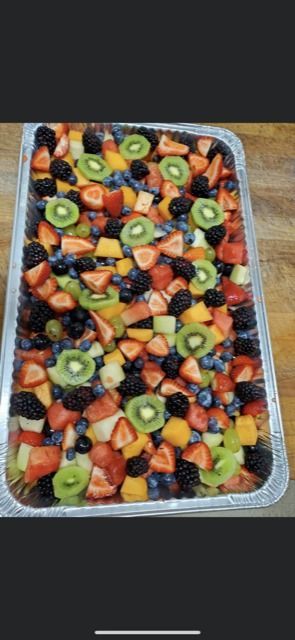 A rectangular tray filled with a colorful fruit salad featuring kiwi, strawberries, blueberries, and blackberries.