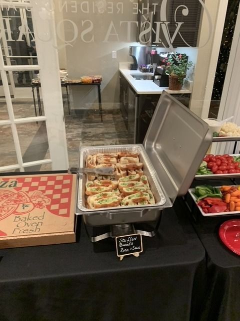 Buffet with pizza slices, bruschetta, and vegetables on a table at a gathering.