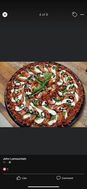 Pizza with toppings on a wooden surface.
