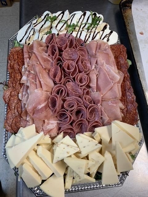 Charcuterie platter with assorted meats, cheeses, and mozzarella with balsamic glaze.