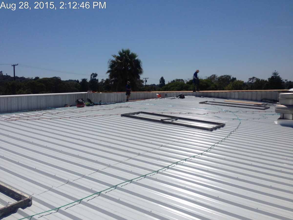 Rooftop with white corrugated panels and skylights under a clear blue sky