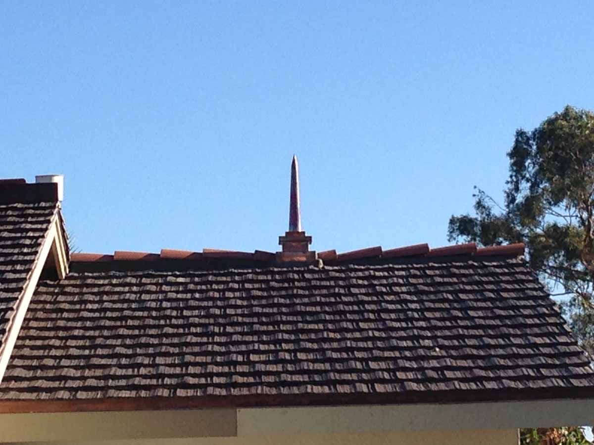 Red-tiled roof with a chimney against a clear blue sky
